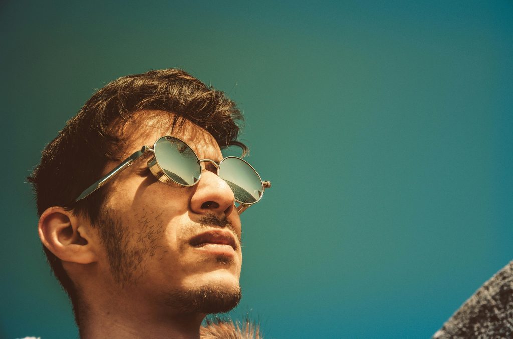 Portrait of a man in sunglasses gazing upward on a clear sunny day.